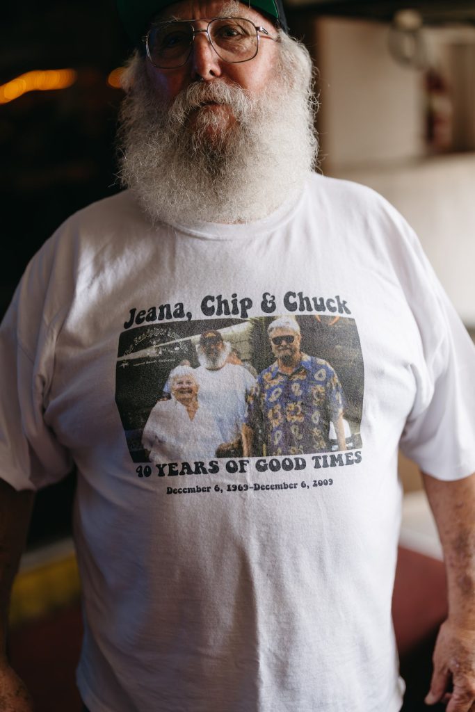 A man with a white beard in a 'Jeana, Chip & Chuck, 50 years of good times' t-shirt inside the bar