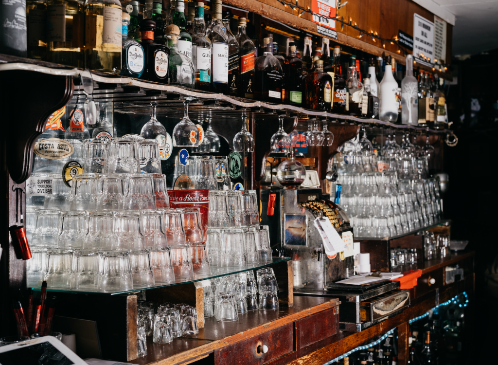Stacked glasses and backlit bottles on the back bar at the Sandpiper Lounge