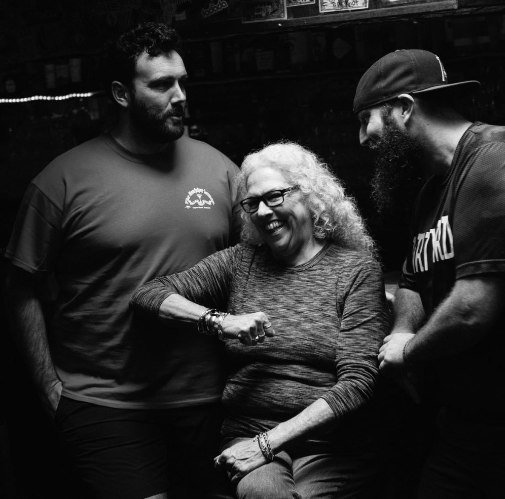 Three people laughing together inside the bar, black and white